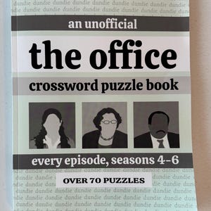 May include: A paperback crossword puzzle book titled "the office" with the subtitle "every episode, seasons 4-6". The cover features silhouettes of three characters and the text "OVER 70 PUZZLES". The background has a repeating pattern of the word "dundie".