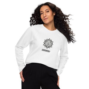 May include: White sweatshirt with a black and white geometric design of a tree inside a star. The text "HARMONY" is printed below the design.