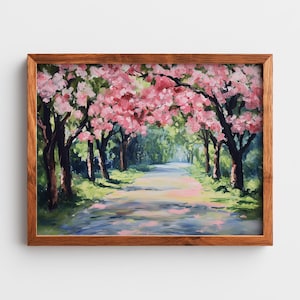 Puede incluir: Pintura de paisaje enmarcada que representa un camino bordeado de árboles. Las ramas de flores rosas se arquean sobre la carretera, con follaje verde y cielo azul. La obra de arte está en un marco de madera.