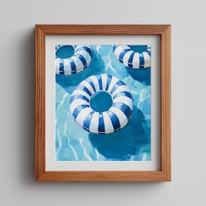 May include: A framed print featuring three blue and white striped inflatable rings floating in a pool of water. The artwork is a painting with a focus on the water's reflections and shadows, creating a summery, vacation theme.