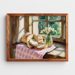 Può includere: Dipinto incorniciato raffigurante una natura morta con pane e fiori. Pane a fette e una pagnotta sono su un panno rosa a scacchi. Un barattolo di vetro contiene fiori bianchi. La scena è ambientata da una finestra.