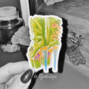 May include: A sticker featuring a whimsical illustration of green high-heeled boots adorned with mushrooms. The boots have orange and blue accents, with purple mushrooms at the base. The text "le Gobline" is at the bottom.
