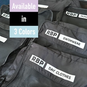 May include: Three black mesh zippered bags with white labels that say "RBP" and "Swimwear", "Day Clothes", and "Pajama".
