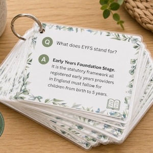 May include: A stack of white flashcards bound by a metal ring, featuring a green leaf border. The top card displays the text: Q: What does EYFS stand for? A: Early Years Foundation Stage. It is the statutory framework all registered early years providers in England must follow for children from birth to 5 years.