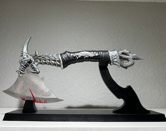 May include: A silver axe with a dragon head design on the blade and handle. The axe is on a black stand with a red accent.