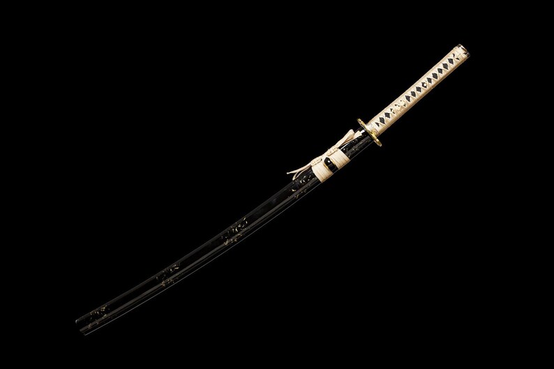 Pode incluir: Uma katana preta com uma empunhadura branca e dourada. A espada &eacute; afiada e tem um design japon&ecirc;s tradicional.