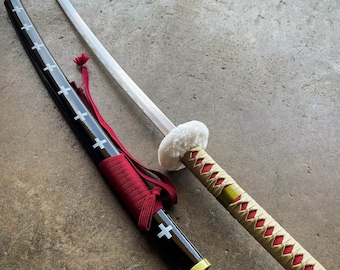 May include: Two swords with black and red scabbards and white and gold handles. The swords are lying on a gray concrete surface.