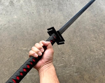 May include: A black katana sword with a red and black wrapped handle. The sword is held by a hand in a grip position.