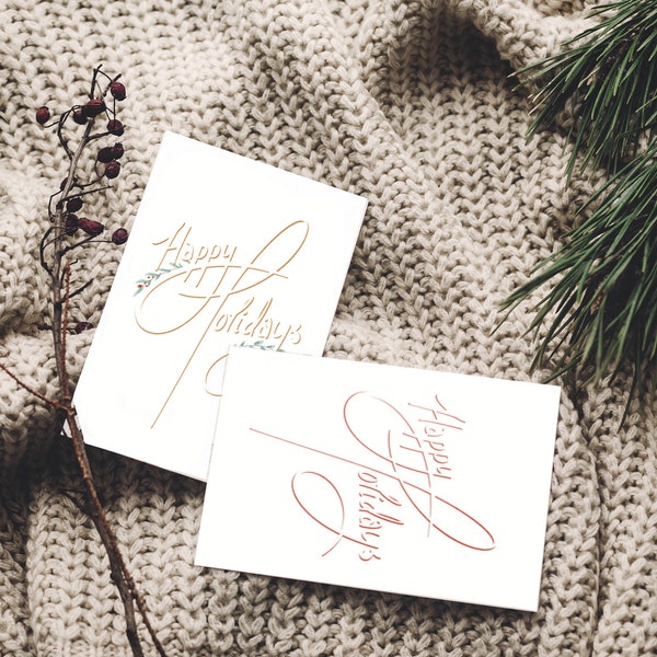 Zum Herunterladen und Selbstausdrucken, Weihnachtskarten: ein Set von zwei Versionen desselben handgeschriebenen Schriftzuges mit der Aufschrift „Happy Holidays“