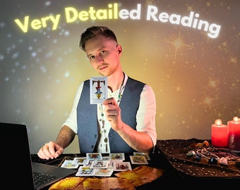 May include: A person holding a tarot card with the text "Very Detailed Reading" above. Several tarot cards are laid out on a black surface, along with a laptop and candles. The person is wearing a vest and a necklace.