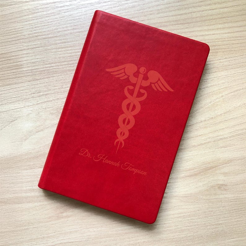 May include: Red leather-bound journal with a gold embossed medical symbol and the name "Dr. Hannah Thompson" on the front cover.