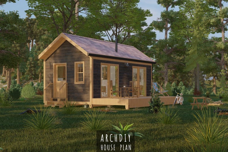 May include: A small, dark-stained wooden cabin with a light-colored roof and trim, set in a lush green forest. The cabin has large windows and a small porch. The text "ARCHDIY HOUSE PLAN" is at the bottom.