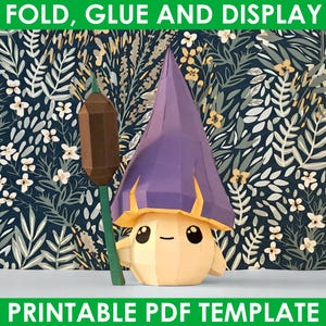 May include: A printable papercraft template of a whimsical character with a purple hat and a brown stick. The character has a yellow body with a smiling face and large eyes. The background is a floral pattern with blue and green leaves. The text "FOLD, GLUE AND DISPLAY" is at the top of the image and "PRINTABLE PDF TEMPLATE" is at the bottom.