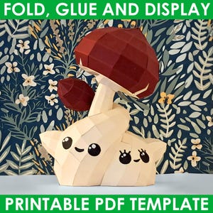 Peut inclure: Modèle de papiercraft imprimable d'un champignon avec un visage mignon. Le champignon est rouge et blanc et a une petite créature blanche souriante en dessous. L'arrière-plan est un motif floral bleu et vert. Le texte "FOLD, GLUE AND DISPLAY" est en haut de l'image et le texte "PRINTABLE PDF TEMPLATE" est en bas de l'image.