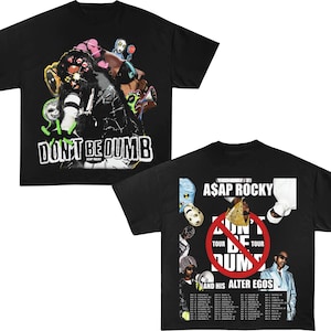 Puede incluir: Dos camisetas negras con gráficos. Una presenta un diseño abstracto y colorido con el texto "DON'T BE DUMB" y "A$AP ROCKY". La otra camiseta tiene "A$AP ROCKY" y "DON'T BE DUMB" con un gráfico de gira y fechas.