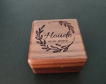 May include: A wooden box with a lid, engraved with a wreath of leaves and the name "Houde" and the date "10.01.2023".