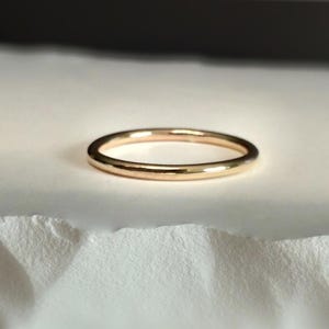 May include: A simple gold band ring, a classic and timeless design.