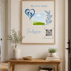 Könnte beinhalten: Ein gerahmtes Wandposter mit dem Text My first Steps, einem blauen Herz mit Babyfußabdrücken, einem quadratischen Fotoplatzhalter, einem blauen Blattzweig, dem Namen Juliana, dem Datum 13.08.2025 und einem QR-Code mit Scan to watch my first steps.