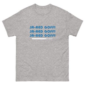 May include: A heather grey t-shirt with the text "JA-RED GOFF!" repeated three times in blue. The text "DETROIT" is printed in white below the repeated text.