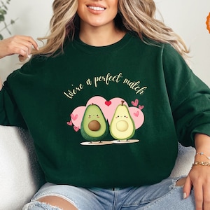 May include: A dark green sweatshirt with the text "We're a perfect match" and a graphic of two avocados with hearts.