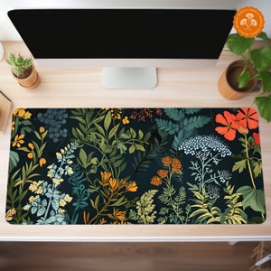May include: A dark blue desk mat with a floral pattern featuring various shades of green, yellow, orange, and red. The pattern includes leaves, flowers, and stems.