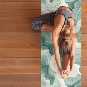May include: A person doing a yoga pose on a green and white patterned yoga mat. The mat has a green and white abstract design.