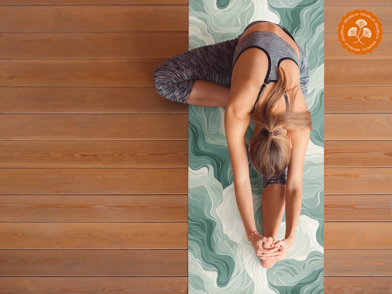 May include: A person doing a yoga pose on a green and white patterned yoga mat. The mat has a green and white abstract design.