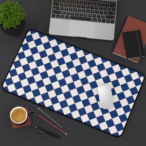 May include: A blue and white checkered mouse pad with a computer mouse on it. The mouse pad is on a black surface with a laptop, a cup of coffee, pencils, and a pen.