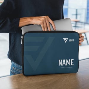 May include: A navy blue laptop sleeve with a black trim. The sleeve has a geometric design and the word "NAME" in white. The logo is a stylized arrow. A person is holding the sleeve with a laptop inside.