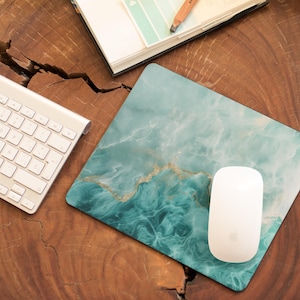 May include: A teal and white marble-patterned mousepad with a white wireless mouse on top. The mousepad is on a wooden surface.