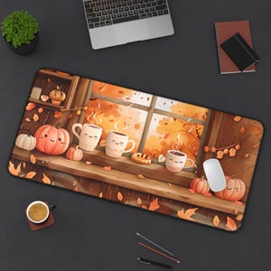 May include: A rectangular desk mat featuring an autumn-themed illustration. The design includes smiling pumpkins, coffee mugs, and a window view of fall foliage. The mat is designed to fit under a laptop and mouse.