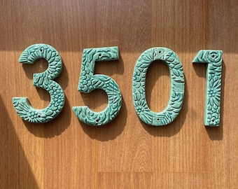 May include: Green ceramic house numbers with a floral pattern. The numbers are 3501.