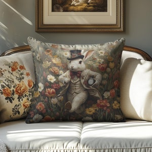 May include: A decorative throw pillow with a white rabbit wearing a top hat and holding a pocket watch. The rabbit is surrounded by colorful flowers and greenery.
