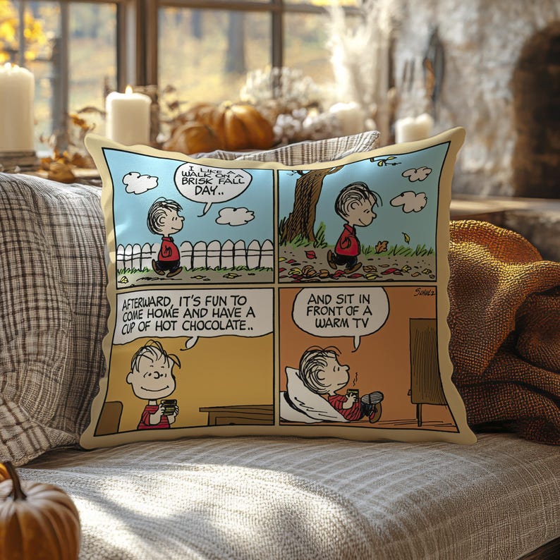 Może przedstawiać: Prostokątna poduszka z komiksem z Linusem z Peanuts. Komiks przedstawia Linusa cieszącego się chłodnym jesiennym dniem, pijącego gorącą czekoladę i relaksującego się przed telewizorem. Poduszka ma beżową obw&oacute;dkę.