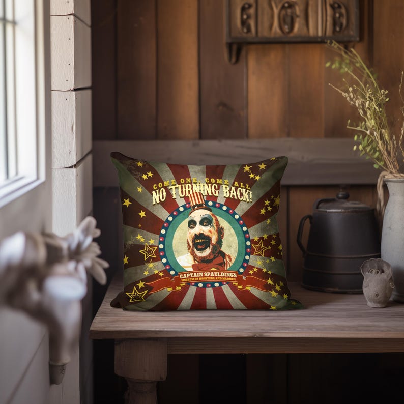 May include: A red, white, and blue throw pillow with a vintage circus poster design. The poster features a clown with a bloody face and the text "Come one, come all, no turning back!" and "Captain Spaulding's Museum of Monsters and Madmen".
