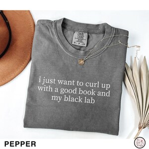 K&ouml;nnte beinhalten: Ein graues Comfort Colors T-Shirt mit dem wei&szlig;en Text "i just want to curl up with a good book and my black lab". Eine goldene Anh&auml;nger-Halskette liegt auf dem Shirt. Das Wort "PEPPER" steht unten.