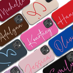 May include: A collection of personalized phone cases with various names written in a cursive font. The cases are in different colors, including pink, blue, red, brown, and black.