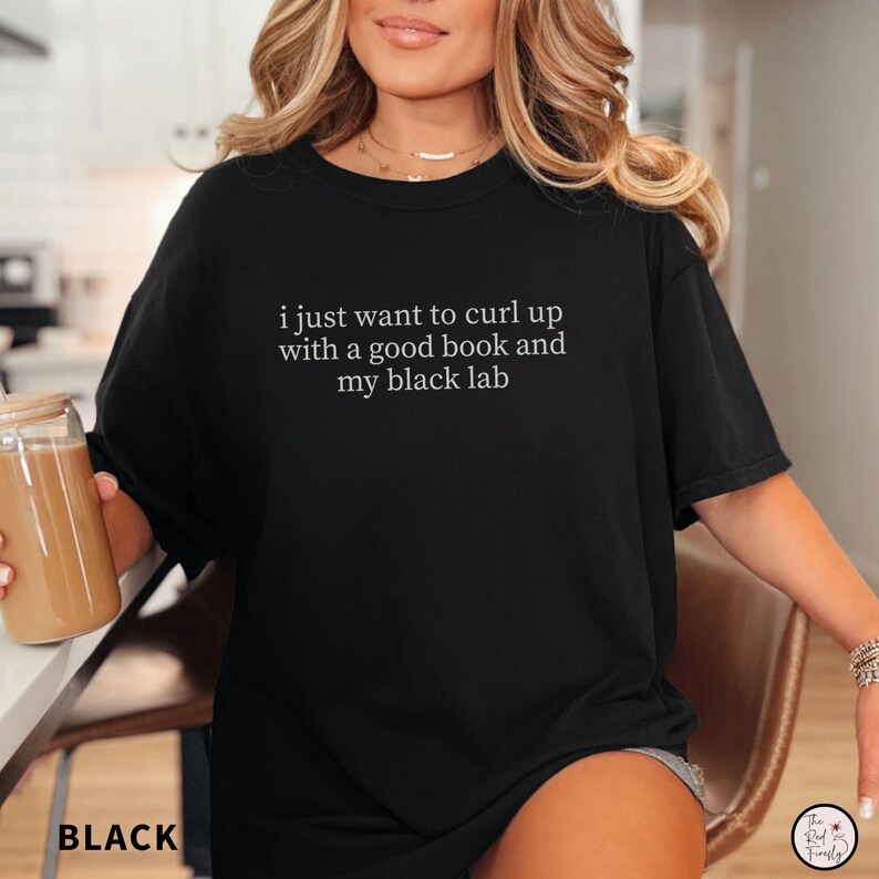 K&ouml;nnte beinhalten: Schwarzes T-Shirt mit dem wei&szlig;en Text "i just want to curl up with a good book and my black lab". Das Wort "BLACK" ist unten links auf dem T-Shirt aufgedruckt.