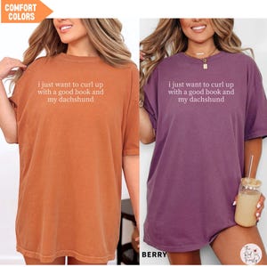 Puede incluir: Dos camisetas de gran tama&ntilde;o, una en naranja quemado y otra en color baya. Cada camiseta tiene el texto blanco "i just want to curl up with a good book and my dachshund" impreso. Las camisetas forman parte de la colecci&oacute;n "Comfort Colors".
