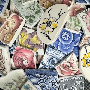 May include: Assortment of colorful ceramic tiles with floral and geometric patterns. The tiles are various shapes and sizes, including squares, rectangles, and ovals. Some tiles feature intricate floral designs in shades of pink, blue, and yellow, while others have simple geometric patterns in black and white.