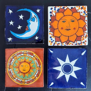 May include: Four square ceramic tiles with colourful designs. The first tile has a blue background with a white crescent moon and stars. The second tile has a white background with a red, orange, and yellow sun with a face. The third tile has an orange background with a yellow sun with a face in a green and orange circle. The fourth tile has a blue background with a white star with a circle in the centre.