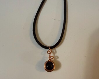 Colgante de ónix negro envuelto en alambre de cobre hecho a mano sobre cordón de seda negra