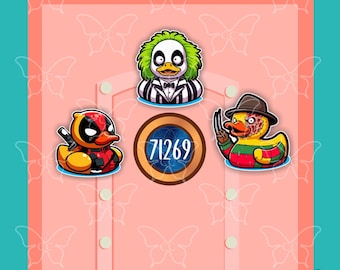 May include: Three rubber duck stickers featuring pop culture characters. One duck has green hair and a striped suit, one is red and black with a mask, and one wears a brown hat and a striped sweater. A circular emblem with the number 71269 is centered.