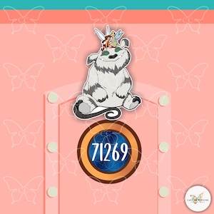 May include: A sticker with a cartoon illustration of a furry, grey and white creature with fairies on its head. The design includes a circular element with the number 71269. The background is pink with butterfly motifs.