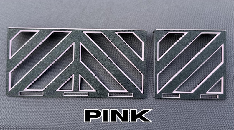 May include: Two dark gray metal pieces with a geometric design and pink accents. The larger piece has a peace sign shape. The word "PINK" is displayed in bold, white letters at the bottom.