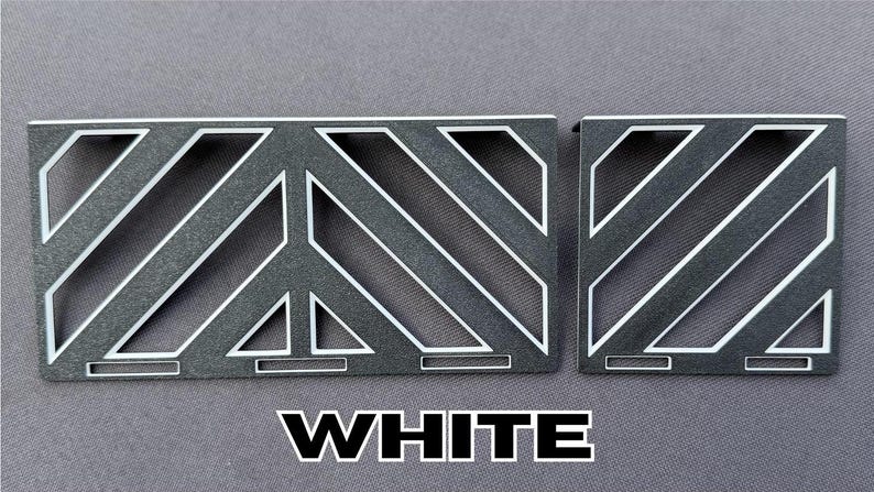 May include: Two gray metal decorative panels with white diagonal and geometric designs. The word "WHITE" is displayed in bold white letters at the bottom of the image. The panels are likely for decorative purposes.