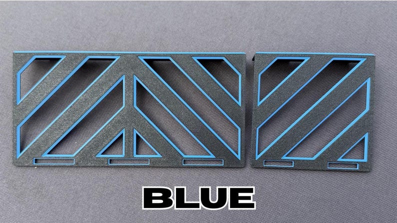 May include: Two geometric, rectangular objects with a black base and blue accents. The design features diagonal lines and a peace symbol shape. The word "BLUE" is written in bold, white letters.