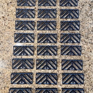 May include: Arrangement of black rectangular objects with a geometric chevron design. The objects are arranged in rows and columns. The text "27 - 7 INCH" is at the bottom of the image.