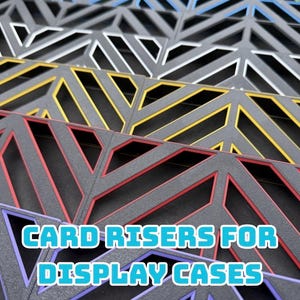 May include: Close-up of colorful card risers for display cases. The risers are in various colors, including red, yellow, blue, and white, with a geometric design. The text "CARD RISERS FOR DISPLAY CASES" is displayed in a blue font.