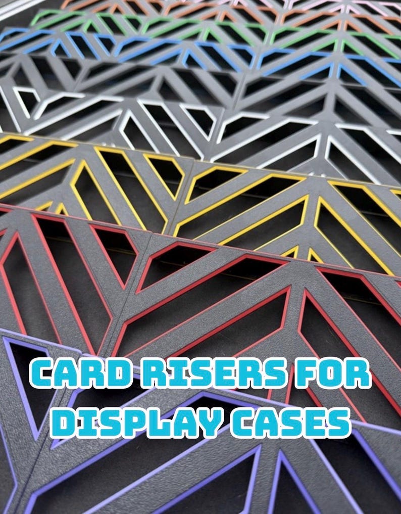 May include: Close-up of colorful card risers for display cases. The risers are in various colors, including red, yellow, blue, and white, with a geometric design. The text "CARD RISERS FOR DISPLAY CASES" is displayed in a blue font.